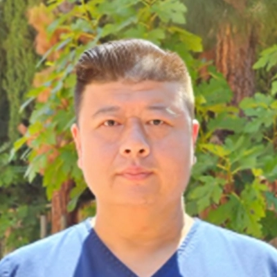 Michael Zhao Smiling In Front Of Leaves